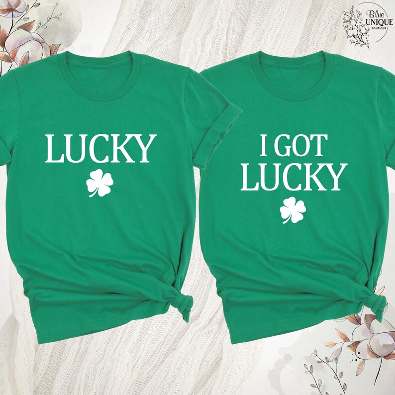 K&ouml;nnte beinhalten: Zwei gr&uuml;ne T-Shirts mit wei&szlig;em Text und einem vierbl&auml;ttrigen Kleeblatt. Ein Shirt sagt "LUCKY" und das andere "I GOT LUCKY". Die Shirts sind aus weichem Material, ideal f&uuml;r St. Patrick's Day.