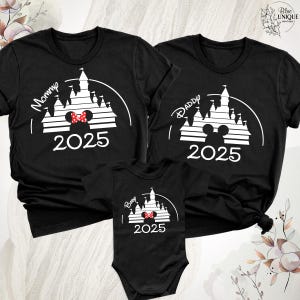 Puede incluir: Camisas negras con siluetas blancas del castillo de Cenicienta, orejas de Mickey Mouse y el texto "Mam&aacute;", "Pap&aacute;" y "Beb&eacute;" con el a&ntilde;o "2025".