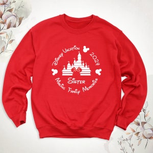 May include: Red sweatshirt with a white graphic design featuring a silhouette of Cinderella's castle, Mickey Mouse ears, and the text "Disney Vacation 2024 Making Family Memories Sister".