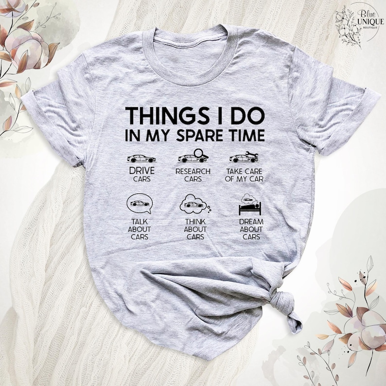 Op de afbeelding: Grijs T-shirt met de tekst "THINGS I DO IN MY SPARE TIME" en een lijst met autogerelateerde activiteiten, waaronder "DRIVE CARS", "RESEARCH CARS", "TAKE CARE OF MY CAR", "TALK ABOUT CARS", "THINK ABOUT CARS" en "DREAM ABOUT CARS".