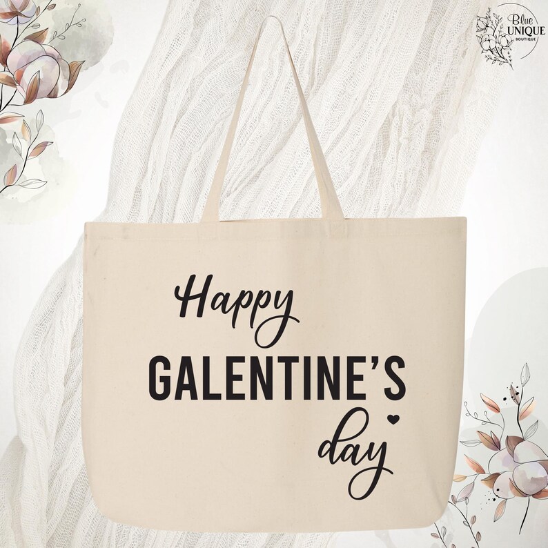May include: Cream-colored tote bag with the text "Happy GALENTINE'S day" in black script and block letters. The bag has two handles and is made of a sturdy fabric. The design includes a small heart.