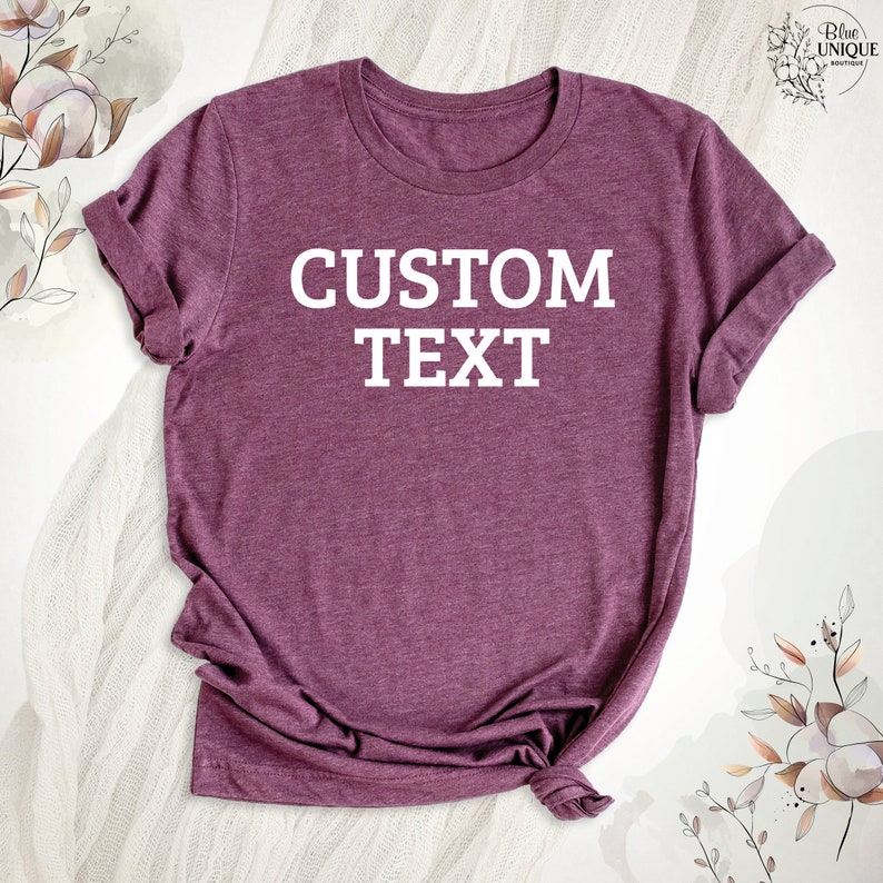 Może przedstawiać: Bordowy t-shirt z nadrukiem "CUSTOM TEXT" w kolorze białym na przodzie.