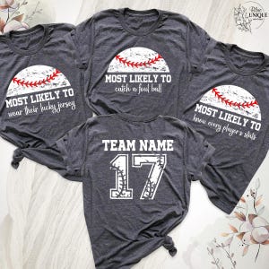 May include: Four dark gray heather t-shirts featuring white baseball graphics with red stitching. Three shirts display text: Most Likely To wear their lucky jersey, Most Likely To catch a foul ball, and Most Likely To know every player's stats. One shirt features Team Name 17.