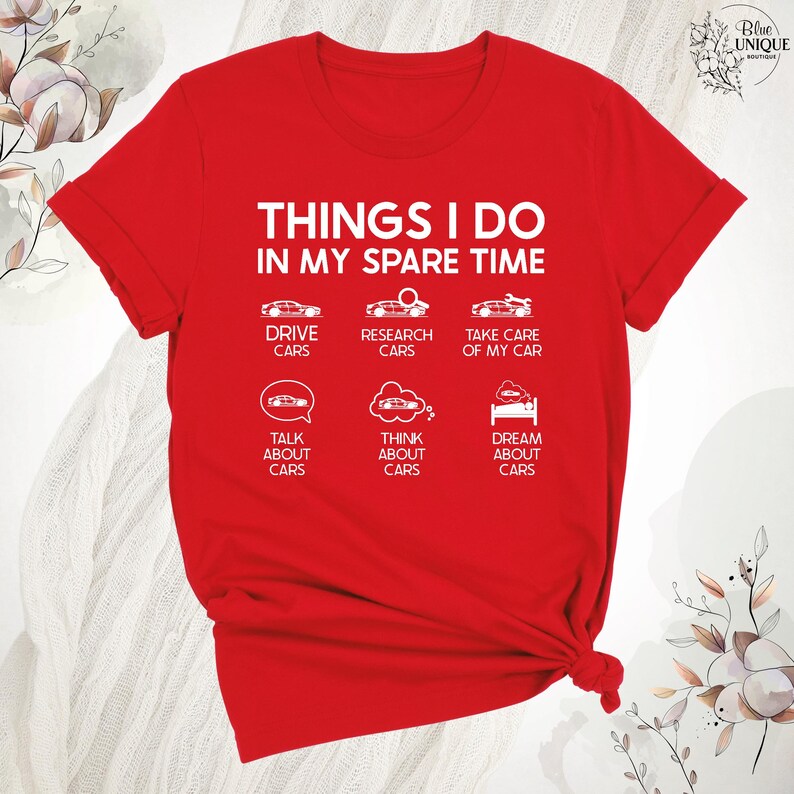 Op de afbeelding: Rood T-shirt met witte tekst die "Things I do in my spare time" zegt. De tekst is gerangschikt in een lijst met auto-iconen. De lijst bevat "Drive cars", "Research cars", "Take care of my car", "Talk about cars", "Think about cars" en "Dream about cars".