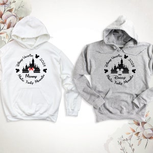 May include: Two hooded sweatshirts, one white and one gray, with a black and white graphic of Cinderella's castle, Mickey Mouse ears, and the text "Disney Vacation 2024 Making Family Memories". One sweatshirt says "Mommy" and the other says "Daddy".