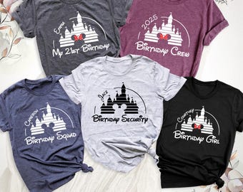May include: Five short-sleeve t-shirts in charcoal, maroon, navy, light gray, and black. Each features a white or black graphic of a castle silhouette with mouse ears and text including "My 21st Birthday," "Birthday Crew," "Birthday Squad," "Birthday Security," and "Birthday Girl."