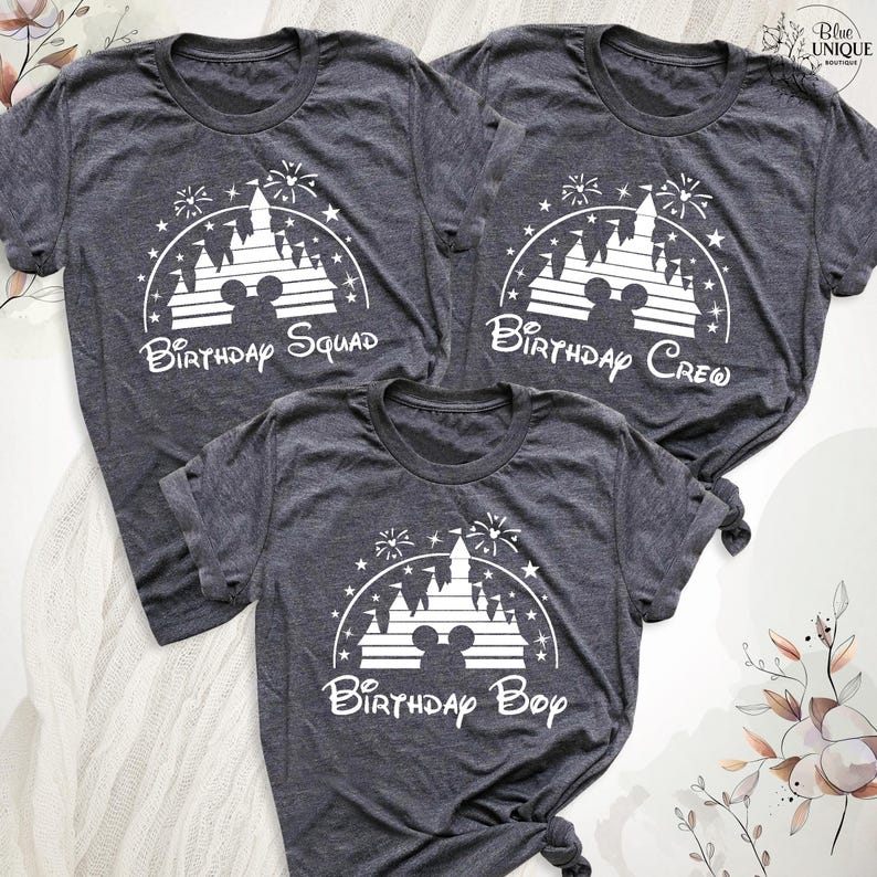 Pode incluir: Tr&ecirc;s t-shirts cinzas com uma silhueta branca do castelo da Cinderela e fogos de artif&iacute;cio. As t-shirts dizem "Birthday Squad", "Birthday Crew" e "Birthday Boy".