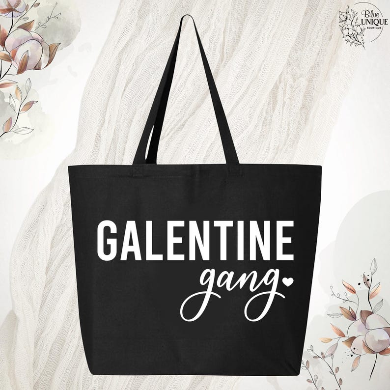 May include: Black tote bag with the words "GALENTINE gang" in white lettering. The bag has two black handles and a heart symbol. The bag is made of a sturdy material.