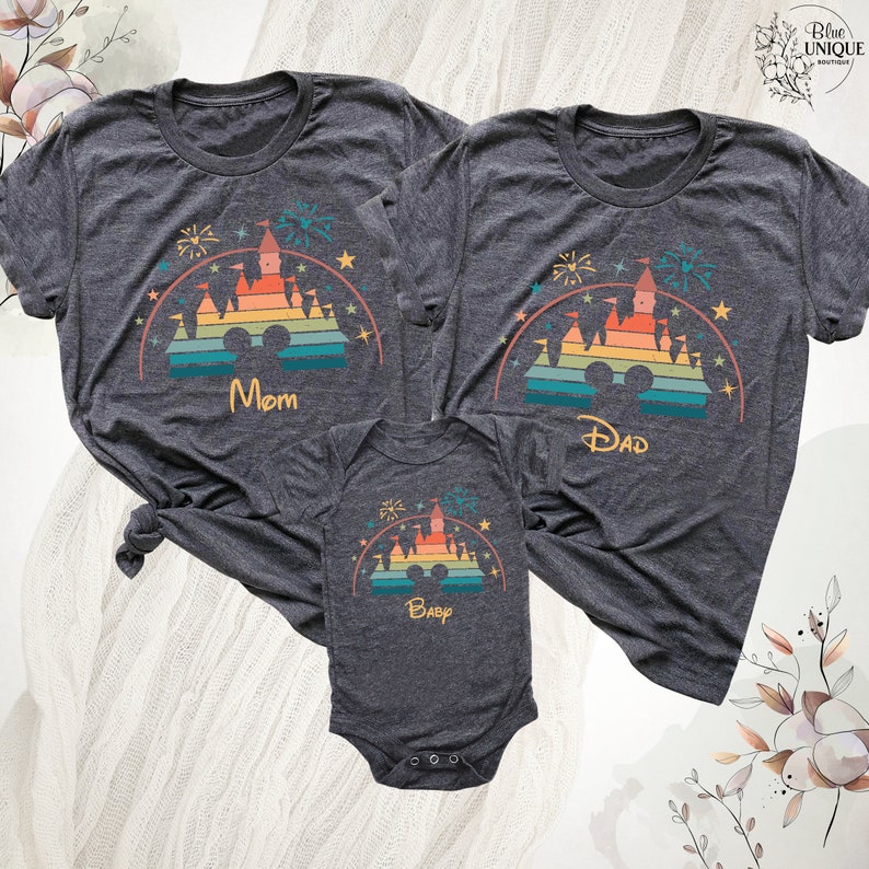 May include: A set of three grey t-shirts featuring a rainbow-colored castle graphic with the words "Mom", "Dad", and "Baby".