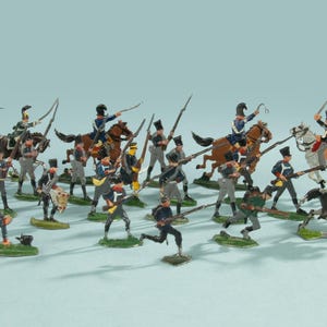Puede incluir: Una colección de soldados de juguete en miniatura, incluyendo infantería y caballería, en varias poses. Las figuras están pintadas en una variedad de colores, incluyendo azul, gris y marrón. Algunos soldados están montados a caballo. Las figuras están sobre bases verdes.
