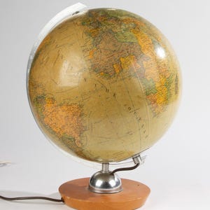 Pode incluir: Um globo terrestre vintage com uma base de madeira e um suporte de metal. O globo é iluminado por dentro e apresenta um mapa detalhado do mundo.