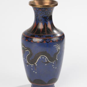 Könnte beinhalten: Eine blaue Cloisonné-Vase mit Drachendesign. Die Vase hat einen dunkelblauen Hintergrund mit einem schwarzen Drachen und weißen Akzenten. Die Oberseite und der Sockel haben dekorative Muster in Rot, Schwarz und Gold.