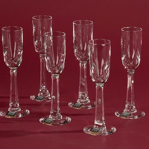 Op de afbeelding: Set van zes heldere glazen champagnefluiten met een delicaat gegraveerd ontwerp. De fluiten hebben een lange, slanke steel en een brede kom.