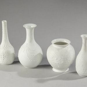 Może przedstawiać: Cztery białe wazony porcelanowe z wytłoczonymi wzorami. Wazony mają różne kształty i rozmiary, a każdy ma unikalny wzór.