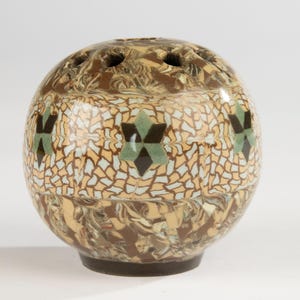 May include: A spherical ceramic flower frog vase featuring a marbled brown and cream base and top section. The center band displays a geometric mosaic pattern of light blue, tan, and dark brown star shapes arranged in a repeating horizontal row.