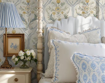 May include: A bedroom scene featuring a four-poster bed with white bedding and decorative pillows with blue accents. A blue-striped lampshade sits on a bedside table with a framed picture and a vase of white flowers. The wallpaper has a floral pattern.