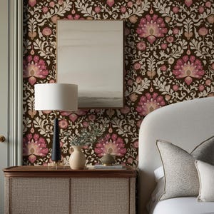 May include: A bedroom scene featuring a dark brown floral wallpaper with pink and white accents. A wooden nightstand with a woven front holds a lamp, vase, and decorative items. A bed with white linens and decorative pillows is visible.
