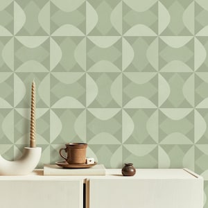 May include: A white ceramic candle holder with a twisted candle, a brown ceramic cup and saucer, and a small brown ceramic jar on a white countertop with a green geometric patterned wallpaper background.