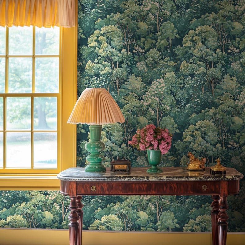May include: A room with a forest-themed wallpaper and a yellow-framed window. A wooden table with a marble top holds a green lamp with a pleated shade, a vase of pink flowers, and decorative objects. The room has a warm, inviting atmosphere.