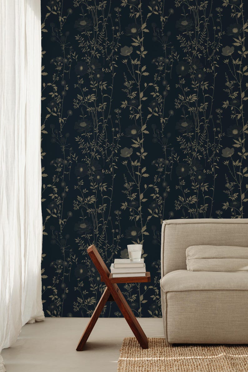 May include: Dark navy wallpaper with a repeating pattern of stylized beige wildflowers and foliage. A wooden side table holds books and a glass of water. A beige sofa and white curtain are also visible.