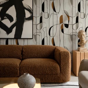 Puede incluir: Un salón moderno con un sofá marrón texturizado, una mesa de centro dorada y una alfombra estampada. La habitación incluye una gran pintura abstracta y un busto sobre una mesa auxiliar de madera, creando un espacio elegante y contemporáneo.