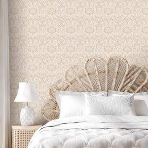 May include: A white bed with a white comforter and two white pillows. The headboard is a large, woven, fan-shaped headboard. The wall behind the bed is covered in a beige wallpaper with a subtle damask pattern.