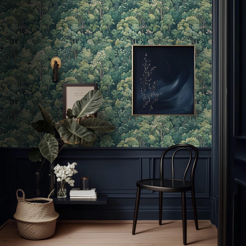 May include: A room with forest-themed wallpaper, dark blue wainscoting, and a black chair. A framed painting with a gold frame hangs on the wall. A woven basket and a plant with large leaves sit on a small shelf.