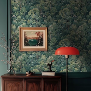 May include: A room with forest-themed wallpaper, a framed landscape painting, and a red lamp. A dark wooden cabinet holds decorative items, including a black bird sculpture and a glass vase with branches.