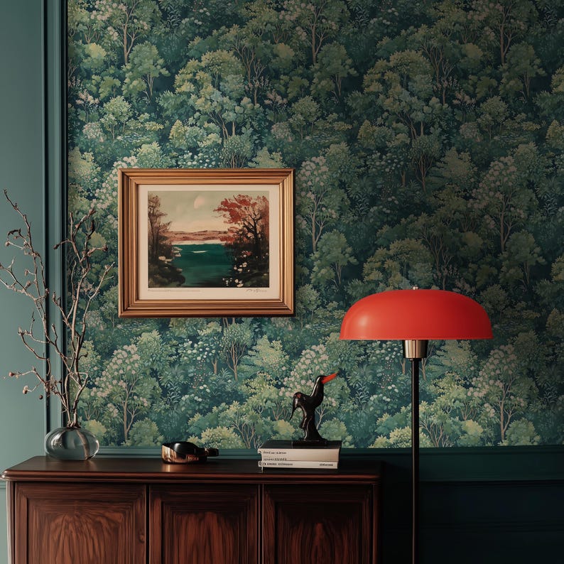 May include: A room with forest-themed wallpaper, a framed landscape painting, and a red lamp. A dark wooden cabinet holds decorative items, including a black bird sculpture and a glass vase with branches.