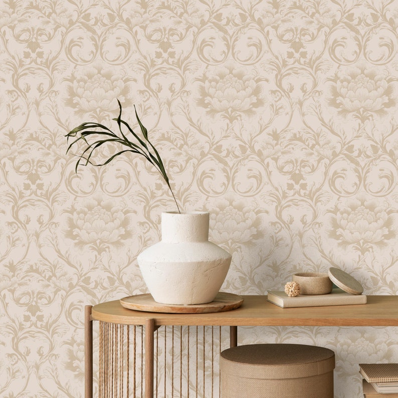 May include: A white ceramic vase with a simple, rounded shape sits on a wooden table against a backdrop of beige wallpaper with a delicate floral pattern.