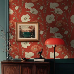 Può includere: Un muro rosso con un motivo floreale bianco. Un dipinto paesaggistico incorniciato è appeso al muro. Una lampada rossa con una base nera si trova su un tavolo di legno di fronte al muro.