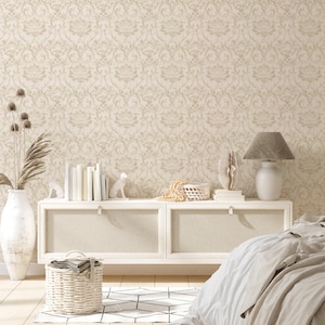 May include: A white dresser with two drawers and a white lamp with a gray lampshade. The dresser is against a wall with a beige damask wallpaper. There is a white rug with a geometric pattern on the floor.