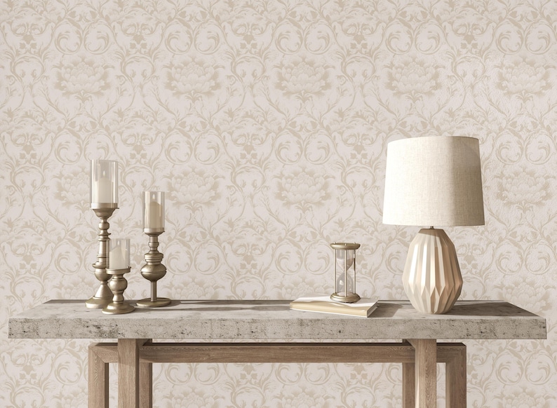 May include: A beige damask wallpaper with a subtle embossed texture. A wooden table with a concrete top features three gold candle holders and a gold lamp with a white shade. An hourglass sits on the table.