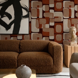 May include: A living room scene featuring a brown, textured sofa, a round, textured vase on a gold-toned coffee table, and a black and white abstract painting. The wallpaper has a geometric pattern in shades of brown and white.