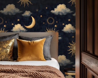 May include: A bedroom scene featuring a bed with a brown knitted blanket and decorative pillows in gold and gray tones. The wall behind the bed is adorned with a celestial-themed wallpaper with suns, moons, clouds, and stars in gold and cream against a dark blue background.