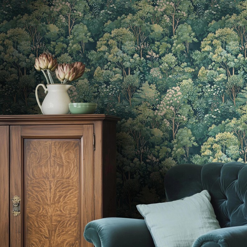 May include: A dark green forest-themed wallpaper covers the wall behind a wooden cabinet, a white pitcher with flowers, and a green bowl. A teal velvet sofa with a light blue pillow is in the foreground.