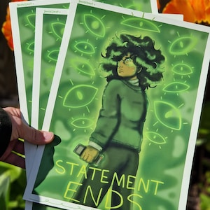 May include: A green and yellow print featuring a person with curly green hair and a green shirt. The person is holding a device with a screen. The background is green with glowing yellow eyes. The text "STATEMENT ENDS." is at the bottom of the print.