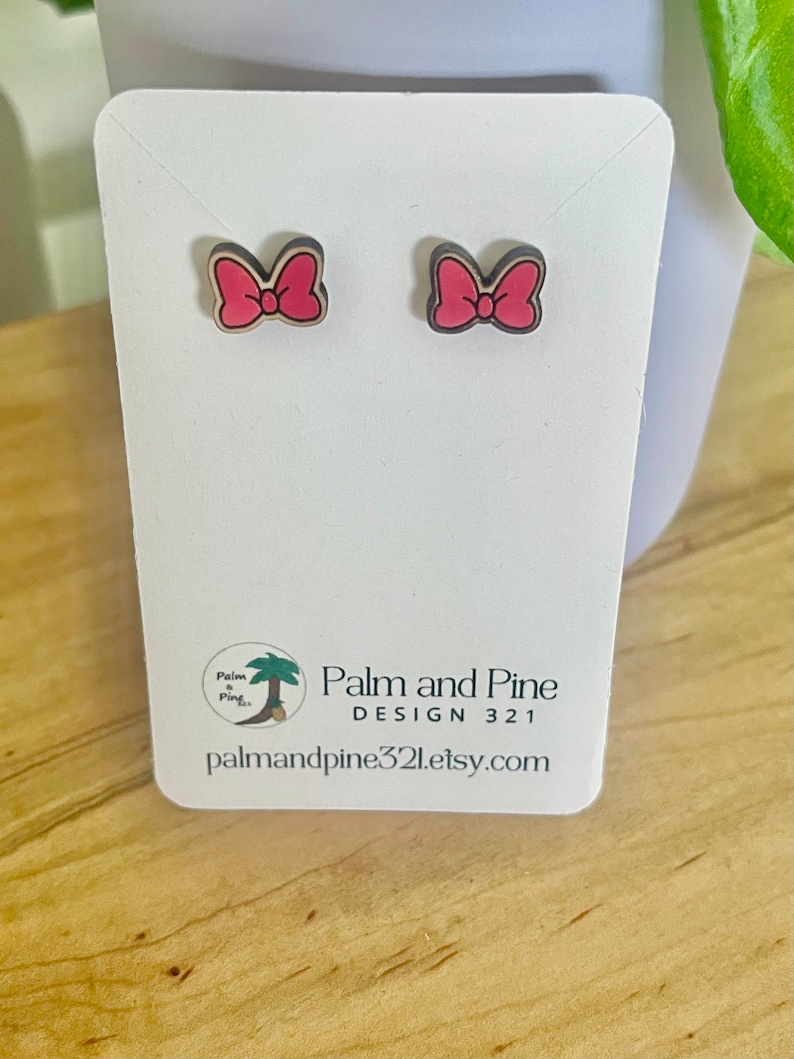 May include: A pair of pink bow earrings on a white card with the text "Palm and Pine Design 321 palmandpine321.etsy.com".
