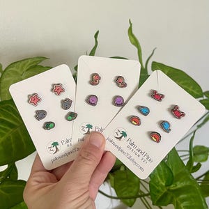 May include: Three sets of wooden stud earrings featuring sea creatures, including starfish, turtles, and crabs. Each set is displayed on a white card with the text "Palm and Pine Design 321 etsy.com" and a logo of a palm tree.