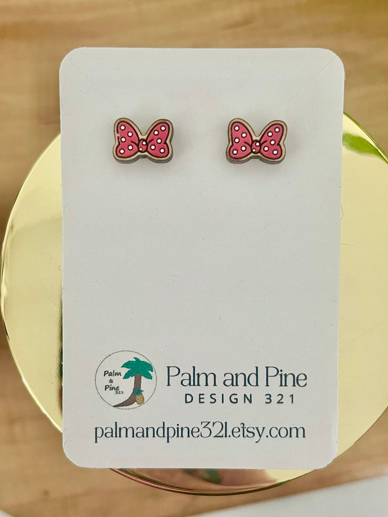 May include: A pair of pink and white polka dot bow earrings on a white card with the text "Palm and Pine DESIGN 321 palmandpine321.etsy.com".