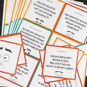 May include: A stack of white cards with orange, green, and red borders. Each card has a question printed on it in black text. The questions are about personal experiences and deep insights. The cards are designed for a game or activity.
