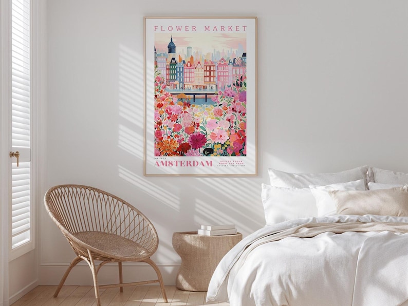 a bedroom with a bed, a wicker chair, and a framed poster of a cityscape with a flower market in the background.