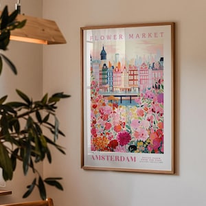 a framed poster of Amsterdam's flower market, with a cityscape and colorful flowers in the background.