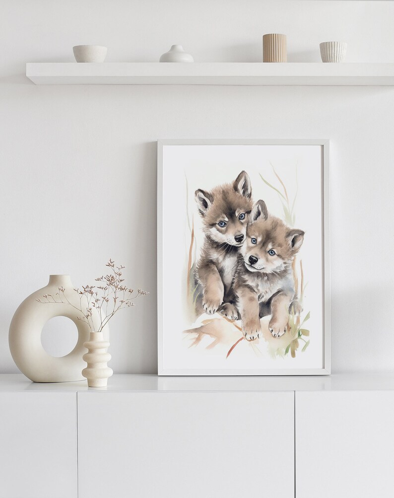 Op de afbeelding: Waterverf schilderij van twee wolf pups die knuffelen. De pups zijn bruin en grijs met blauwe ogen. De achtergrond is lichtgroen en wit.