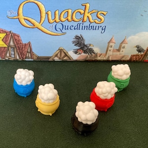 May include: Five colorful cauldrons with white foam on top. The cauldrons are blue, yellow, red, green, and black.