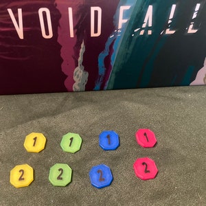 Puede incluir: Siete fichas de juego para un juego de mesa. Hay cuatro fichas con el número "1" en ellas. Una ficha es amarilla, una es verde, una es azul y una es roja. Hay tres fichas con el número "2" en ellas. Una ficha es amarilla, una es verde y una es azul.