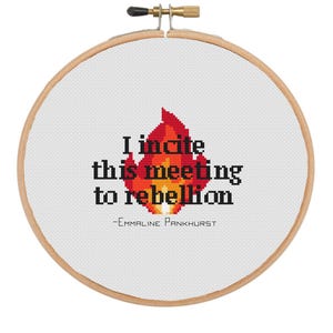 May include: A white embroidery hoop with a red and orange flame design and the text "I incite this meeting to rebellion - Emmaline Pankhurst".