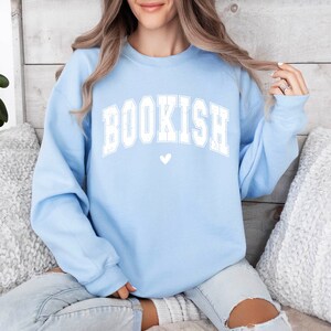 May include: A light blue sweatshirt with the word "BOOKISH" in white letters and a small white heart below it.