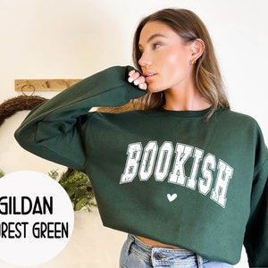 May include: A forest green Gildan sweatshirt with the word "BOOKISH" in white with a distressed look. A small white heart is below the word.