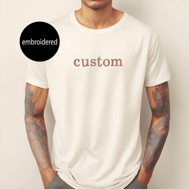 May include: White t-shirt with the word "custom" embroidered in brown on the front.